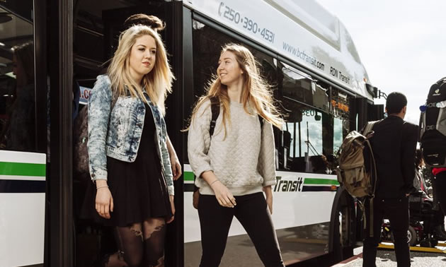 Two students getting off bus. 