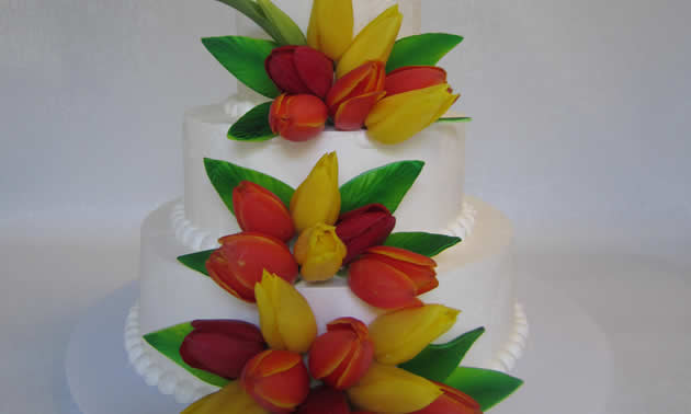 Three tiered white wedding cake, decorated with yellow and red flowers