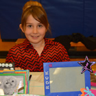 Smiling young girl behind a table bearing decorated picture frames