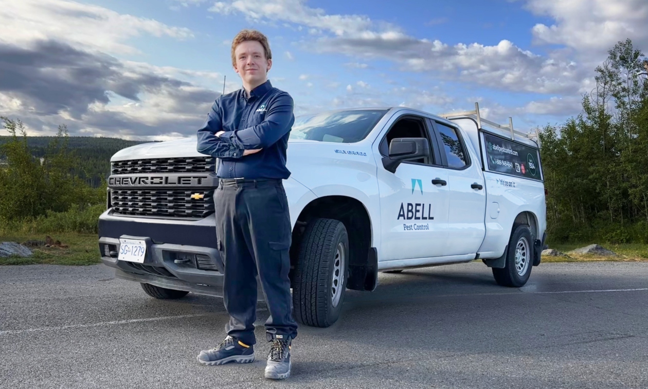 Pest control technician standing in front of a white company vehicle with Abell Pest Control on the side