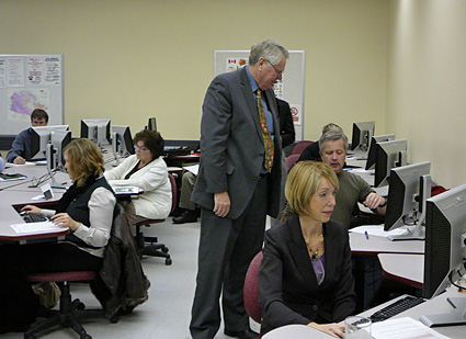adults sit at computers in college classroom