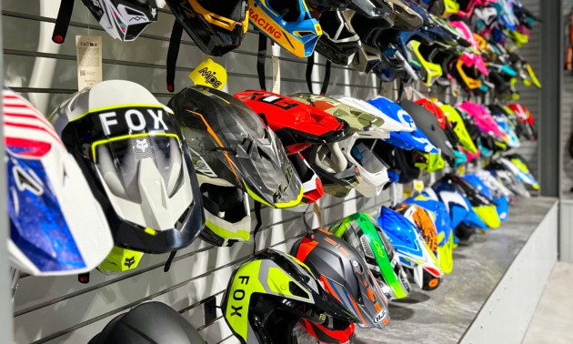 A lineup of motorsports helmets displayed for sale on the wall at All Seasons Motorsports
