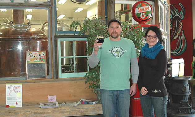 A man holding a glass of beer up and a women standing beside him. 