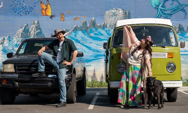 Man, woman and dog in front of a Volkswagen van