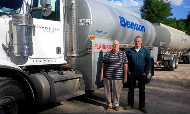 Two men standing beside a fuel truck. 