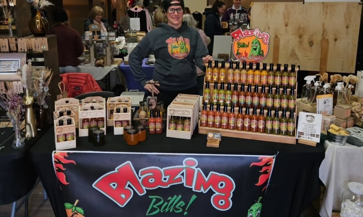Billi-Jo behind a counter with all her hot sauce bottles