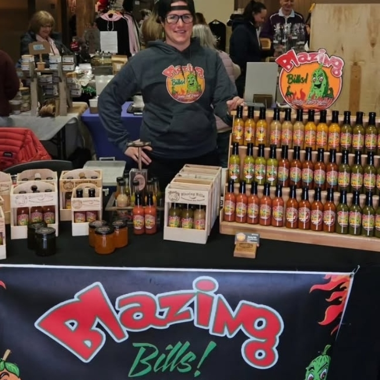 Billi-Jo behind a counter with all her hot sauce bottles