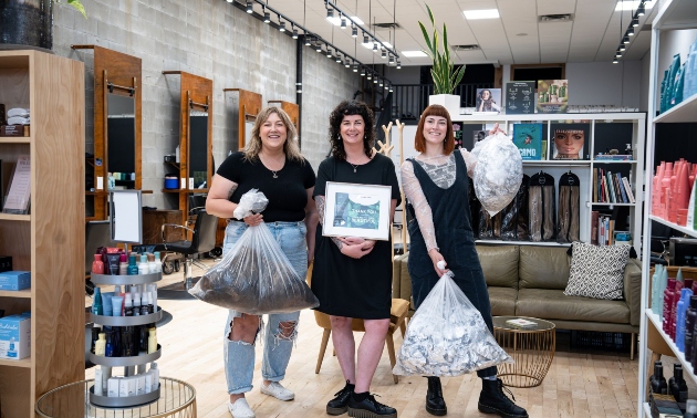 Three stylists holding bags of recycled materials
