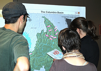 Three people stare at a map of the Columbia Basin.