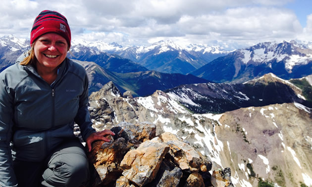 The author is sitting on top of Mount Brewer near Invermere with a sea of mountains in the background.