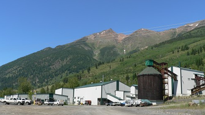 Picture of the Bull River Mine, with buildings in the foreground and a mountain in the background. 