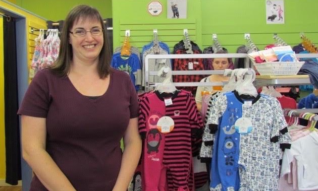 Megan Lescanec stands next to some baby clothes in her store, the Bumble Tree. 