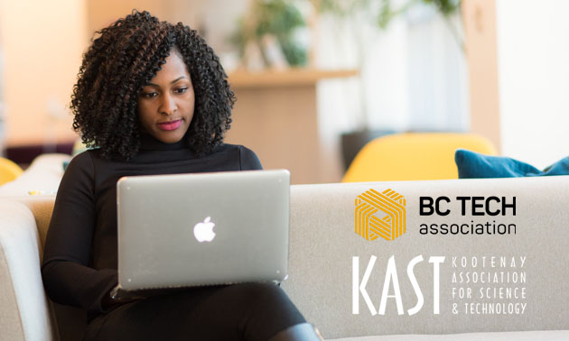 Woman sitting on couch looking at laptop. 