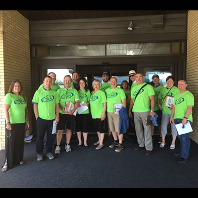 Group of Business Walk members, dressed in bright green t-shirts, heading out to local businesses. 