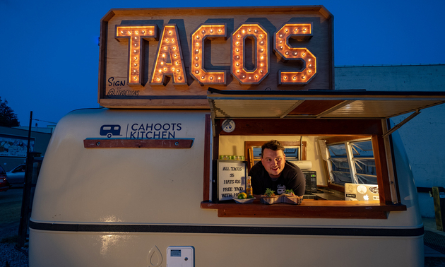 A taco truck with the owner, Spencer Moores, leaning out the window