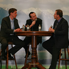 Three man at a table with microphones.