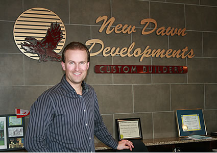 A man stands beside a desk and company sign.