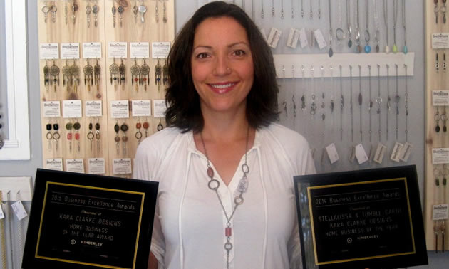 Custom jeweler Kara Clarke has won several chamber awards from the Kimberley Chamber of Commerce including Home Business of the Year. She stands in front of a wall full of hanging necklaces.
