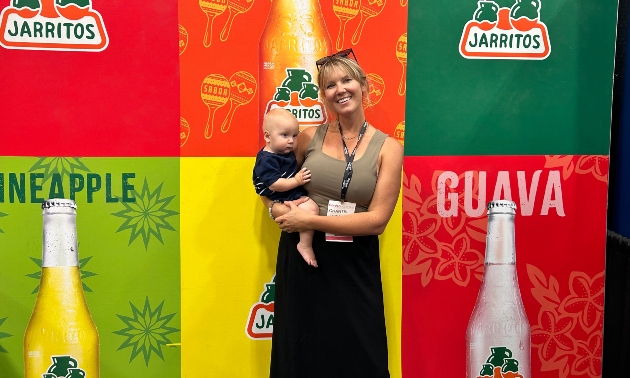 Chantel holding her child standing by a colourful wall