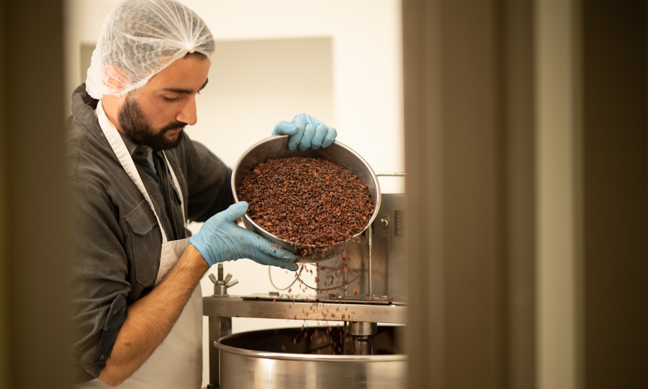 Man pouring cacao beans into a vat