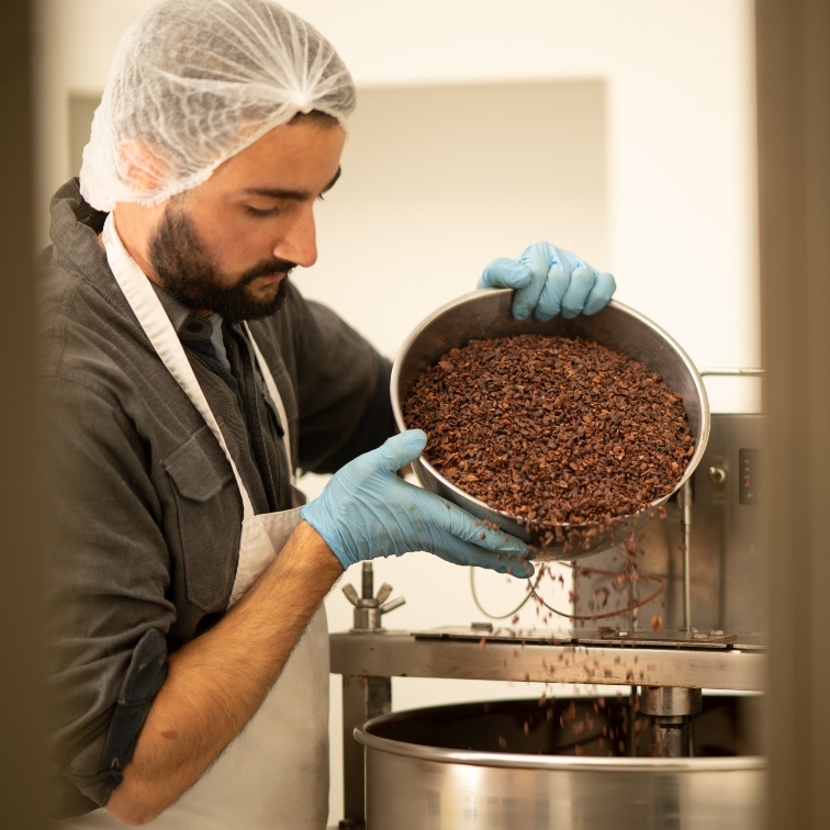 Man pouring cacao beans into a vat