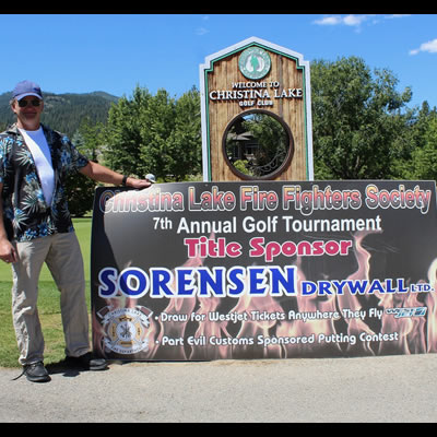 Rob Sorenson poses with last year’s golf tournament banner. 