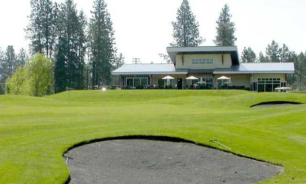 Sand trap in the foreground, with golf clubhouse in the background of picture. 