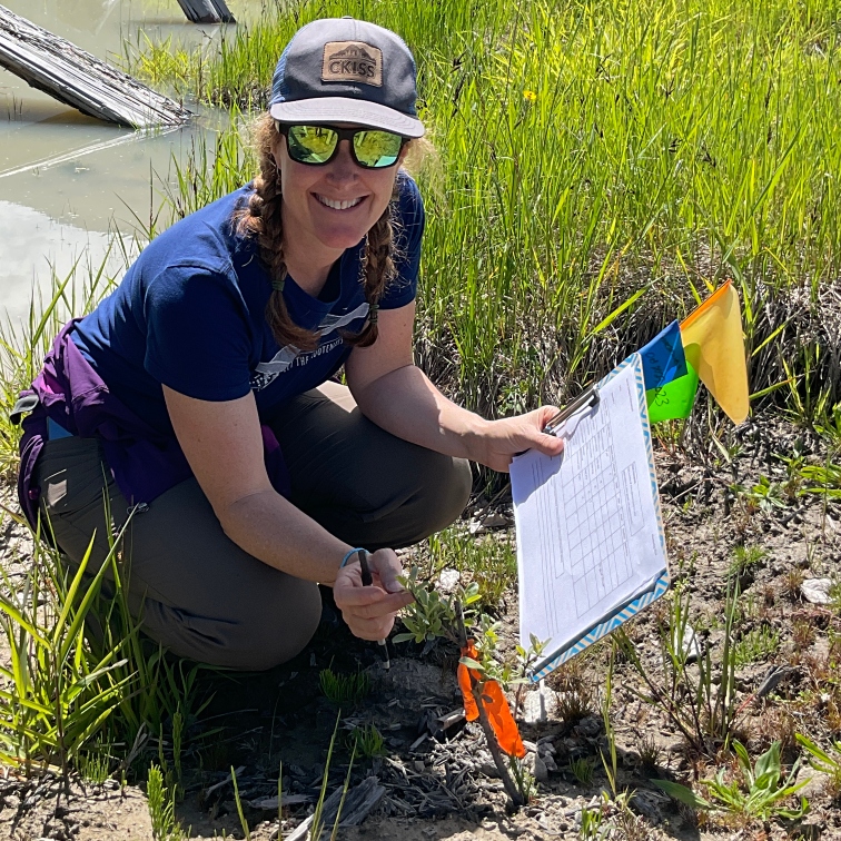 Laurie kneeling down with a clipboard, doing environmental sampling