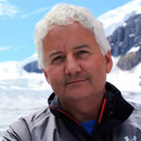 Dale Donaldson stands against the background of a snowy peak.