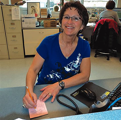 lady sitting at a desk taking notes and smiling