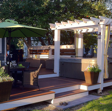 A deck by Rigby Built Construction, complete with a pergola, hot tub, and dining and living areas.
