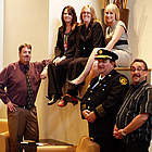 Photo of a group of people posing for a photo. Three women are sitting on a ledge and below are three men. 