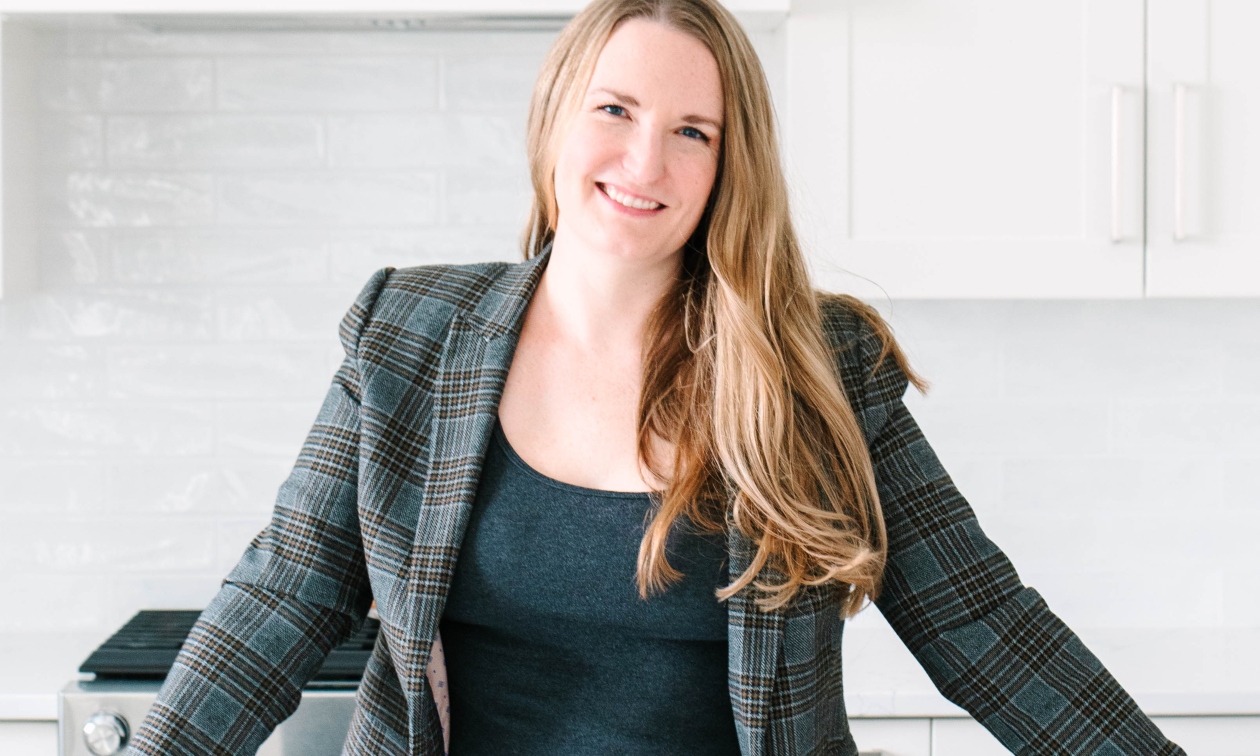 Alexis wearing a blazer, leaning on a counter