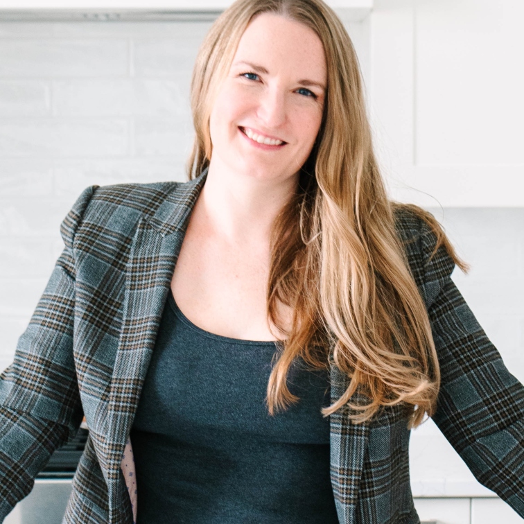 Alexis wearing a blazer, leaning on a counter