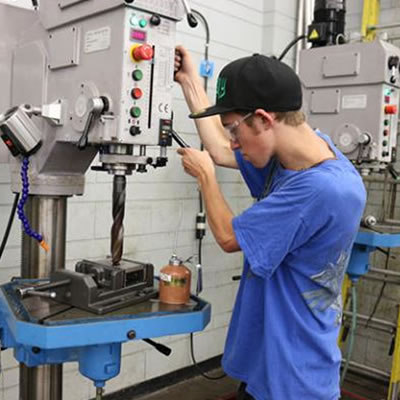 Selkirk College Millwright/Machinist Program student Josh Carr works on the new industry-standard drill press. 