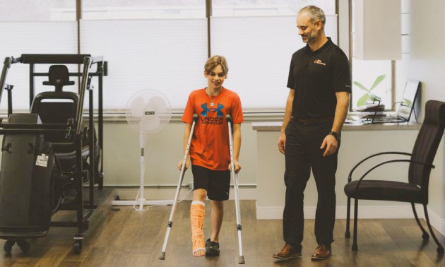 David helping a young person on crutches with physical therapy