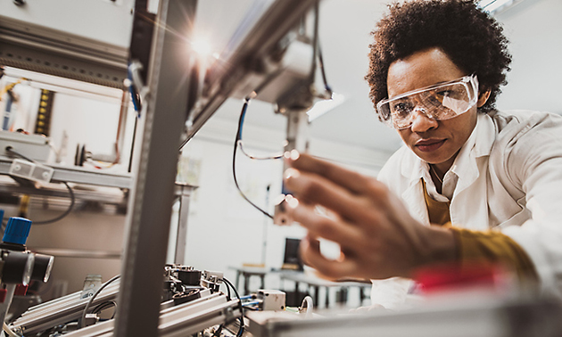 A woman scientist is in a laboratory with a piece of equipment.