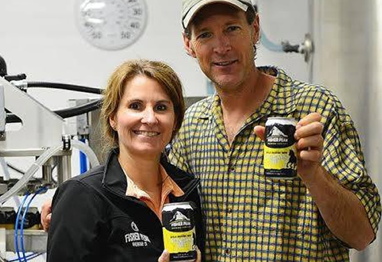 Owners of Fisher Peak Brewing Company holding cans of beer. 