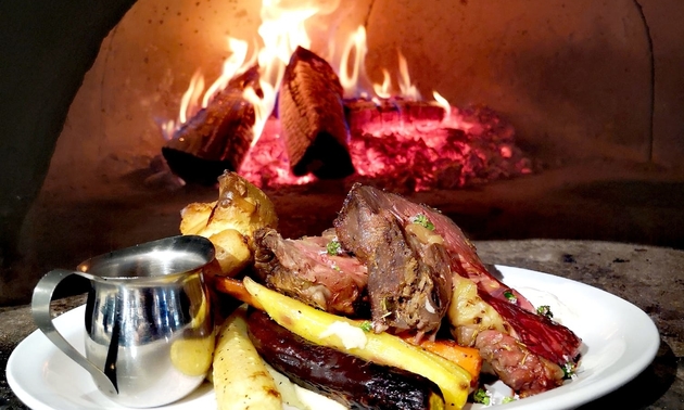 roasted carrots and meat coming out of a wood-fire oven