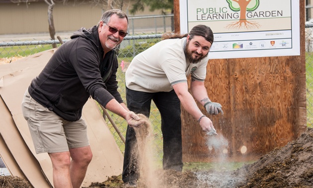 Michael Dean (L) and his son Andrés spread two types of rock dust on the Learning Garden in Grand Forks. Andrés is now general manager of Gaia Green Products.