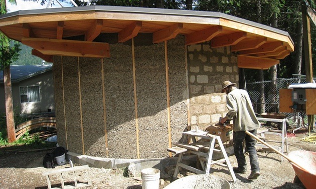 A man working on plastering over bricks on a green building project situated in Art Gibbon Park in Nelson, B.C.