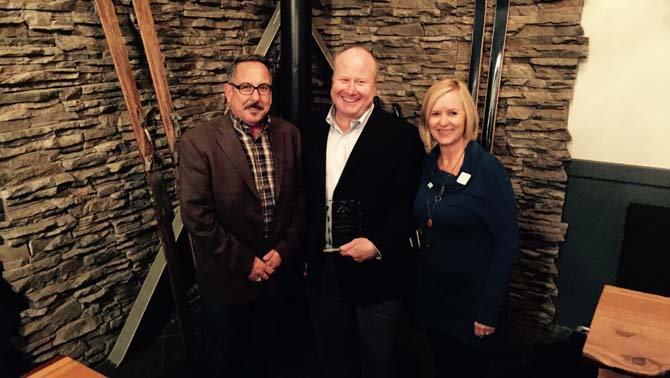 Tom Tischik (left), new chair of Kootenay Rockies and Kathy Cooper (right), Chief Executive Officer of Kootenay Rockies Tourism present Michael Anderson of the True Key Hotels and Resorts in Radium Hot Springs with the Business Person of the Year award.