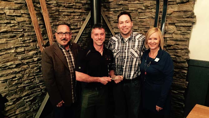 Tom Tischik (left), new chair of Kootenay Rockies Tourism and Kathy Cooper (right), Chief Executive Officer of Kootenay Rockies Tourism present owner Darrin DeRosa and Chef Corey Fraser of the Cedar House Chalets in Golden with the Tourism Business of the Year award.
