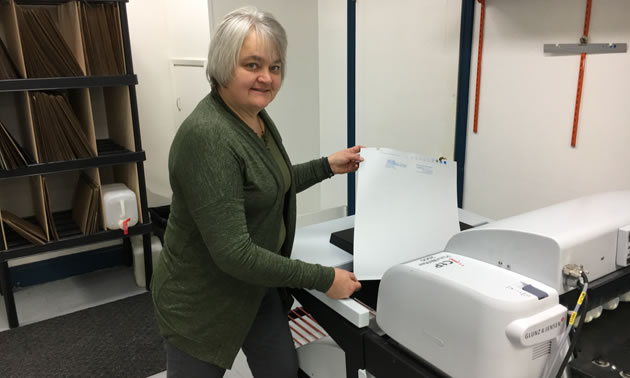 Ingrid Hope, president/owner of Hall Printing, stands beside an environmentally friendly, energy-efficient printer that uses no processing chemicals or water. 