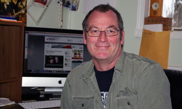 a man with glasses smiling.