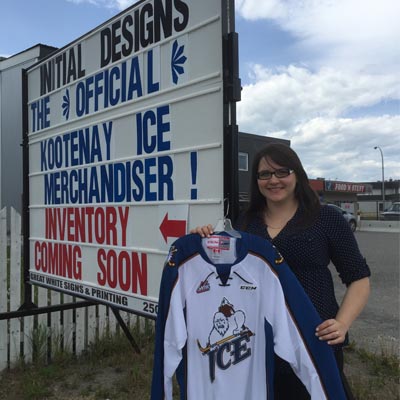 Melissa Hambalek stands in front of her business holding a Kootenay Ice hockey jersey. 