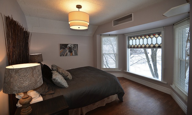 A bedroom that has been staged.  It has neutral colours on the walls, has no blinds or curtains, and no personal details on the walls. 