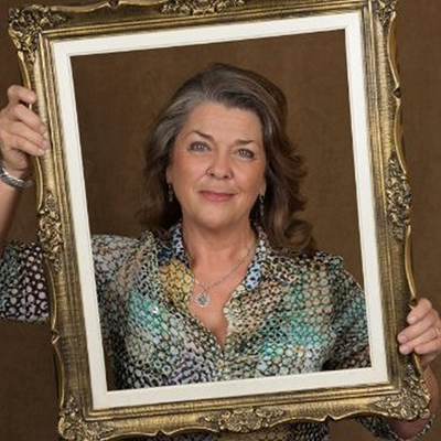Picture of Jan Klimek, holding up decorative frame around herself. 