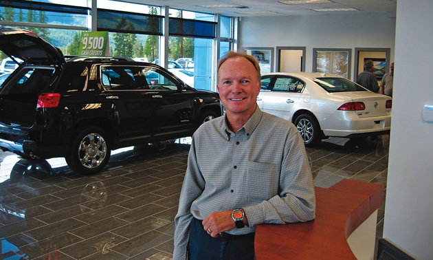 man standing in front of a couple of cars in a showroom