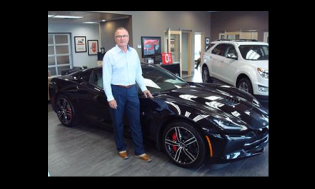 Jim Barber standing beside a black car. 